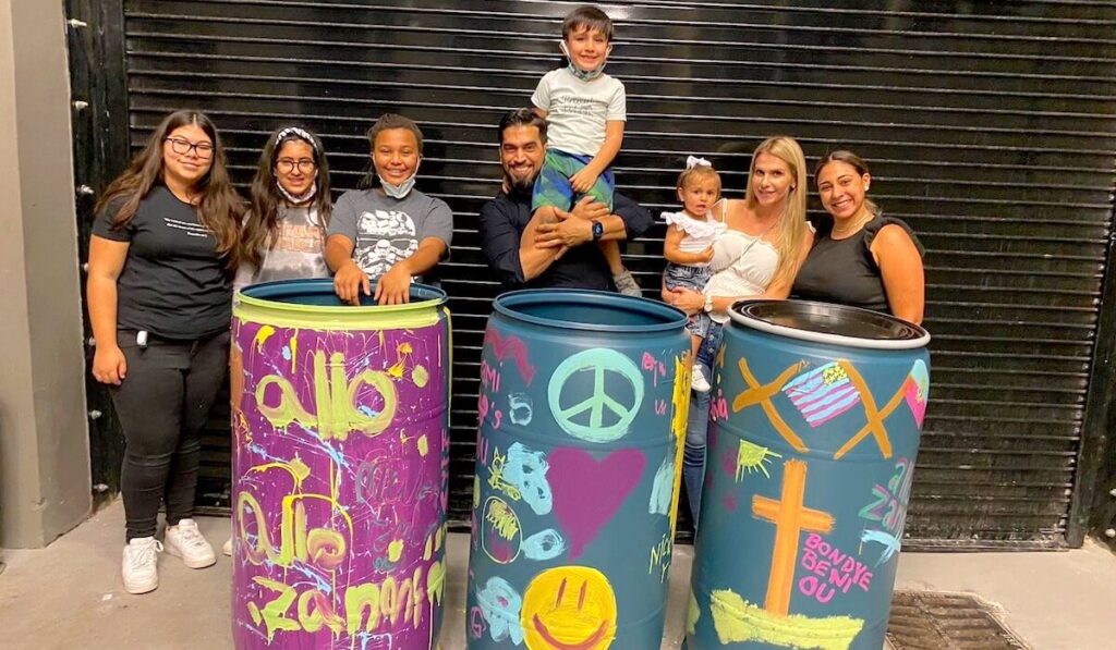 Decorated barrels full of food with the volunteers from It's 4 the Kids who packed them.