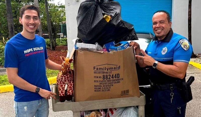 A police officer and a volunteer with a bunch of kids of toys