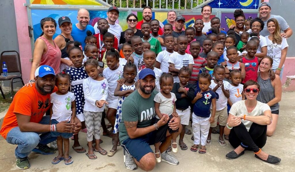 Volunteers with a group of children at an orphanage in Haiti all smiling at the camera.