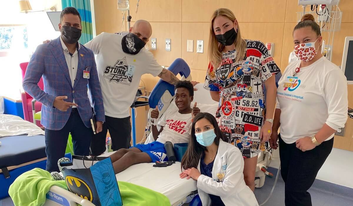 4 adults and a doctor hanging out with a child in a hospital bed