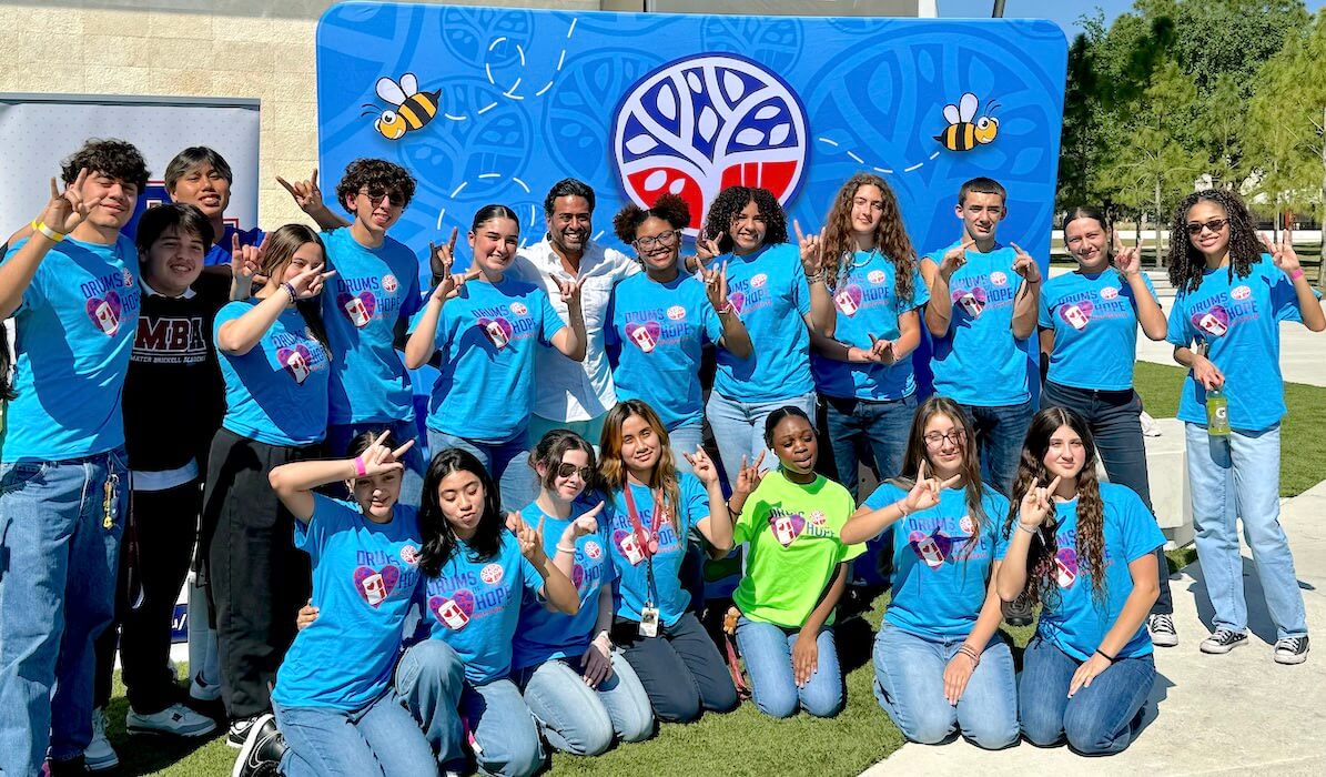 A group of volunteers wearing blue in front of the It's 4 the Kids background